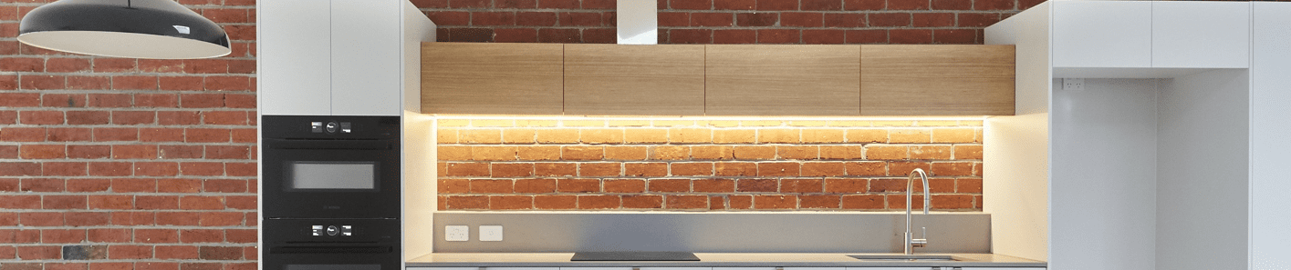 Modern kitchen cabinetry featuring exposed brick for blending old and new home designs.